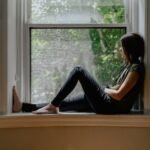 a woman sitting on a window sill