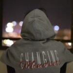 person wearing gray and red hooded jacket facing back